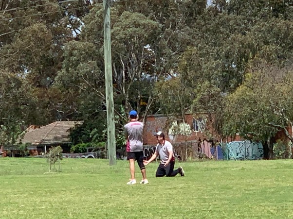 Rev on his knees, F1 with arms folded looking unimpressed even though only his back is showing