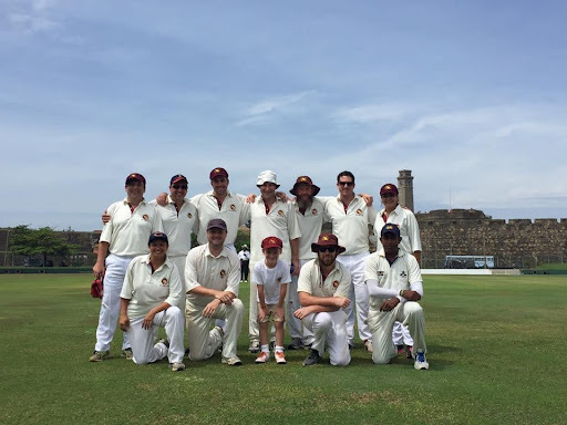 Slightly older men in cricket whites in a team photo mid pitch on Galle ground Sri Lanka